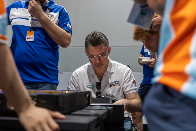 Photo of Johan Ward working at a computer with World Solar Challenge participants looking on.
