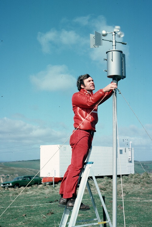 Scientist on a step ladder reaching up to wind instrumentation