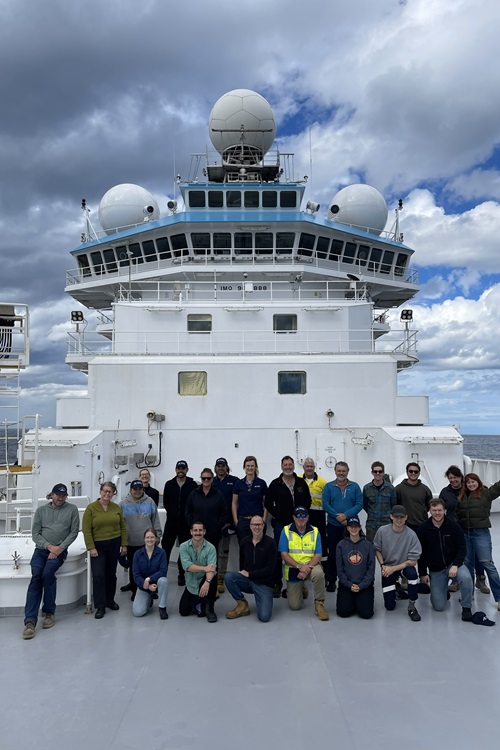 A group of people gathered on the deck of a ship for a group photo.