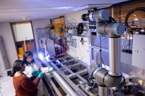 A photo taken from overhead looking down at two people working in a lab with industrial equipment