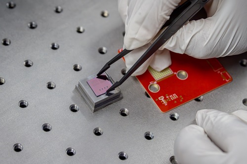 A researcher uses precision tweezers to position a device during laboratory testing and packaging.