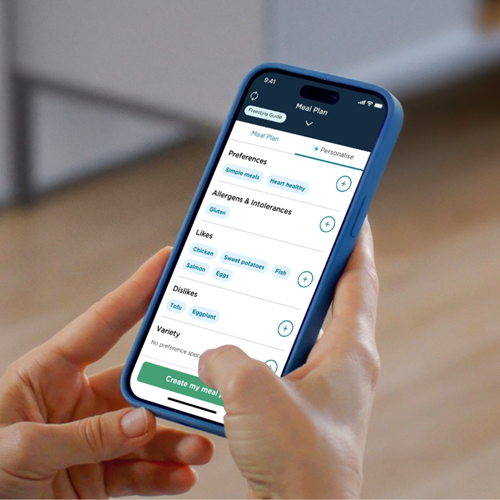 A person is holding a smartphone displaying a meal plan customisation screen from the CSIRO Total Wellbeing Diet app. 