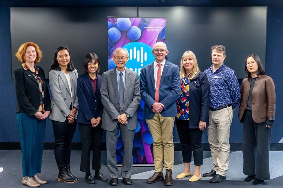 Group shot of eight people standing in front of a large pull up banner. 