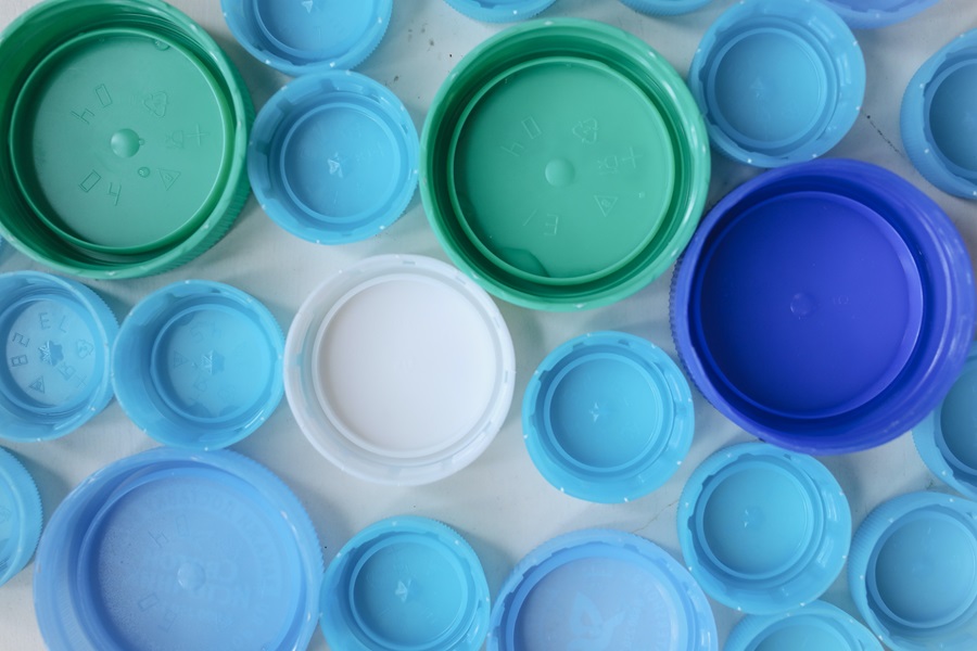 Plastic lids of various colours laid out neatly. 