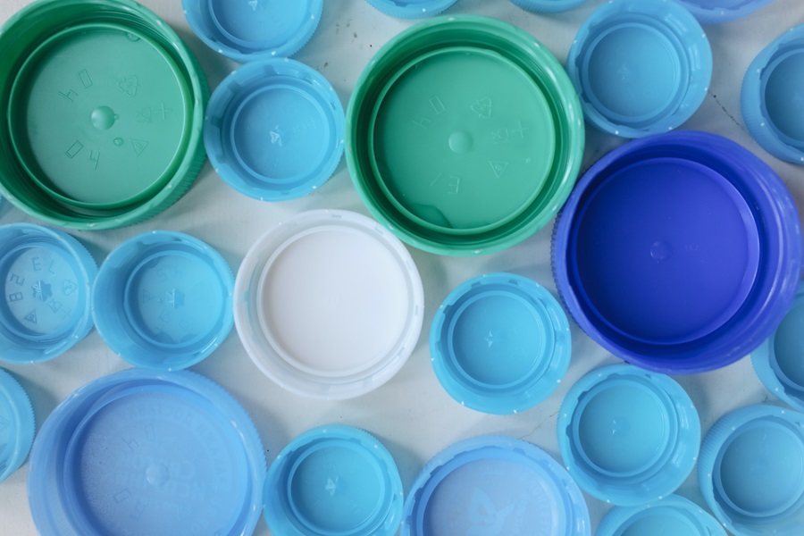 Plastic lids of various colours laid out neatly. 