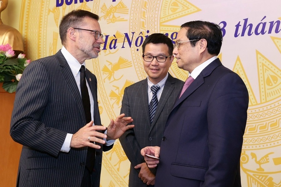 Three poeple standing together talking in front of a large event banner. 