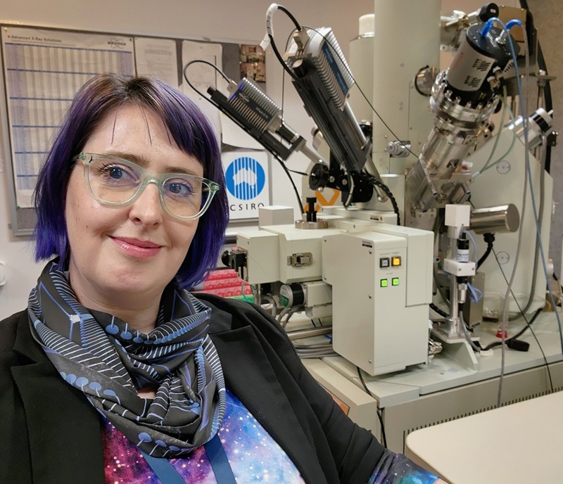 Woman with purple hair sitting in front of microprobe instrument
