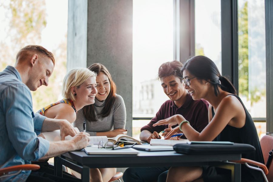 University students talking and studying around a table.