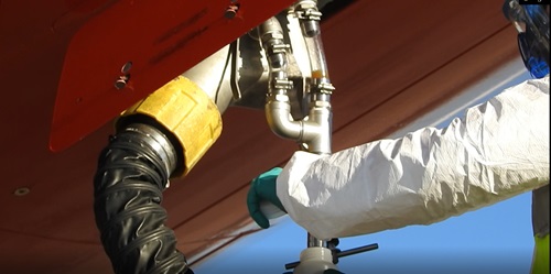 Qantas developed a sampling trap for collecting wastewater samples from planes to avoid cross contamination from flight to flight. Man using sampling trap to get wastewater from planes. Image courtesy of Qantas. 