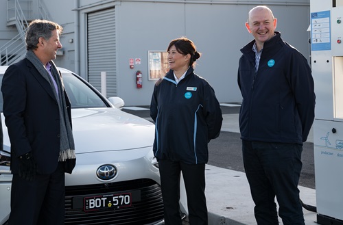 Three people stand in front of a car