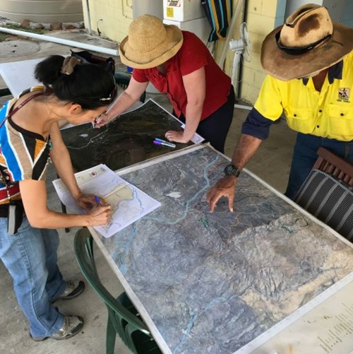 Three people looking over a map on a table 