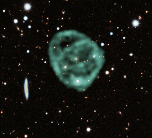 Faint circles in green in the centre of the image, with many dots and bright points of galaxies around them on a black background.