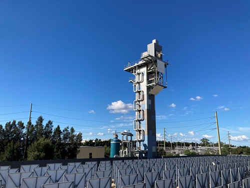 A tall tower stands behind a solar field