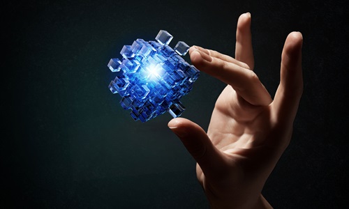 Hand holding a glowing structure made up of multiple plastic cubes. 