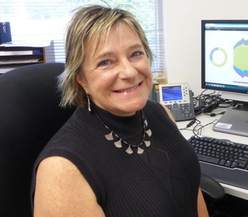 Dr Cecile Paris sitting at her computer desk, smiling at the camera