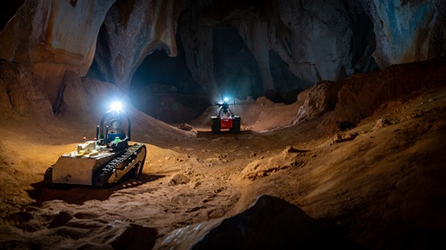 Two robots wheeling through a cave.