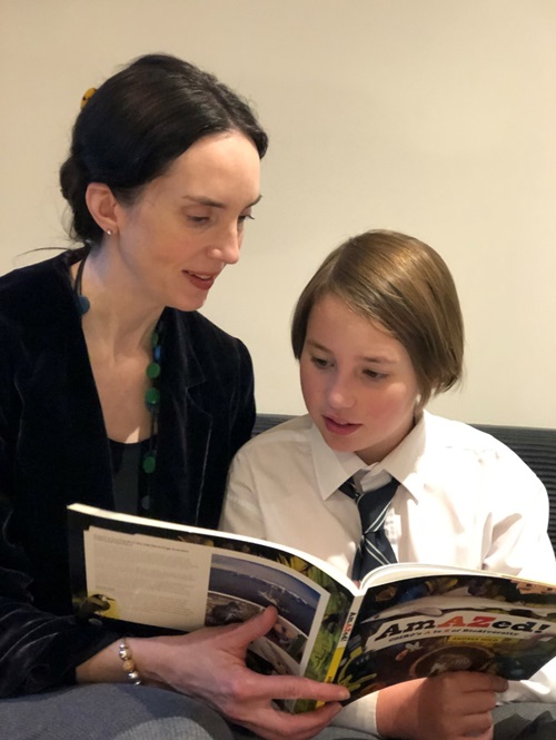 Mother and son sit on couch with book