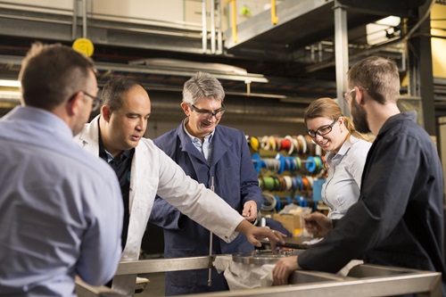 Five researchers gather around a steel disc