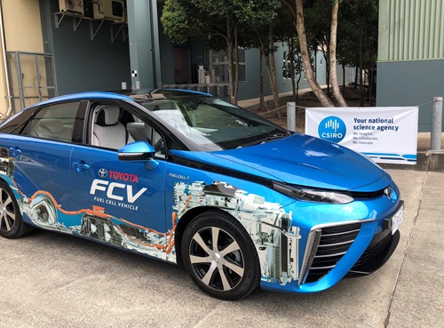 A car with hydrogen branding in front of a building