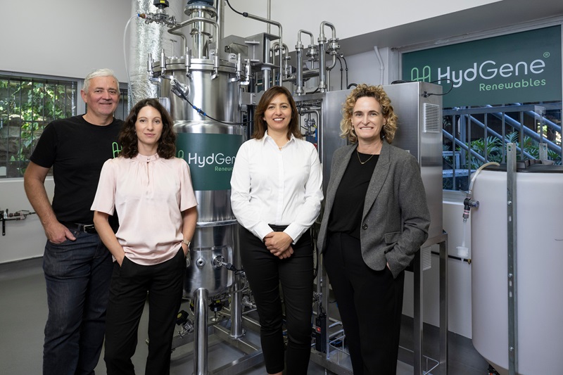 The HydGene Renewables team stands alongside the company's hydrogen generation technology at its renewable hydrogen demonstration facility.