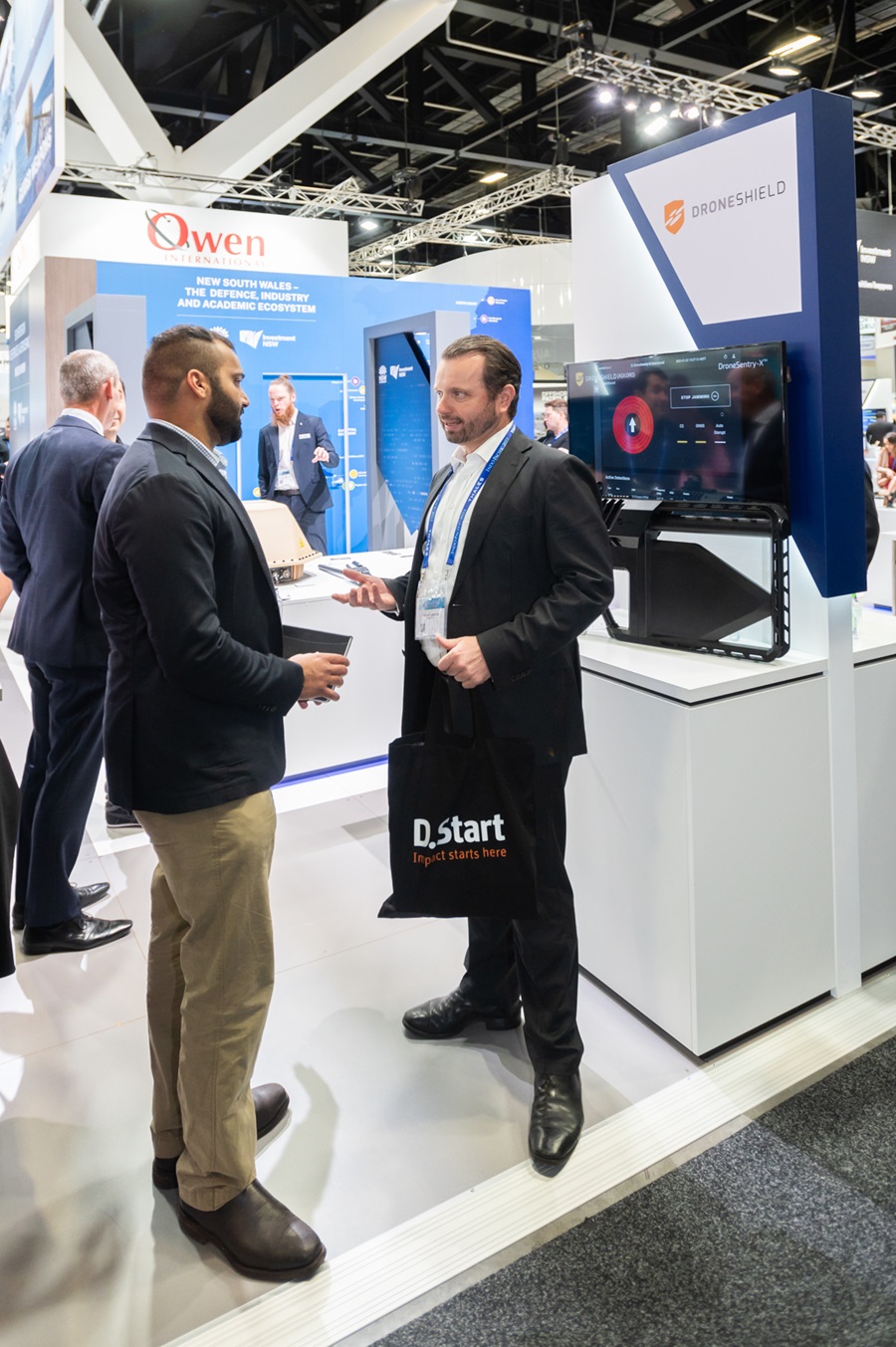 Two men stand at a trade exhibition.