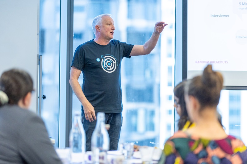 A man standing at the front of the room presenting. 
