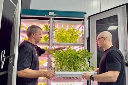 Members of Rainstick carrying a tray of seedlings out of an incubation fridge.
