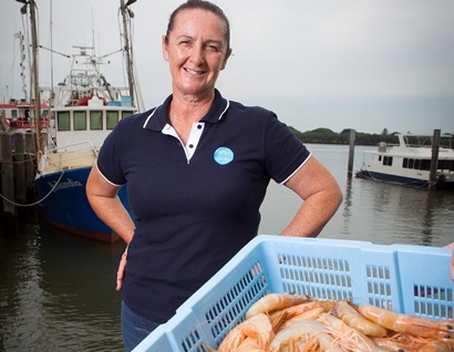 Woman wearing a CSIRO polo shirt standing behind a tray of prawns