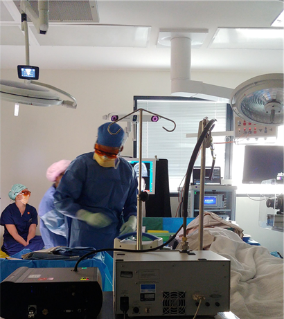 Healthcare worker with mask, gown, gloves and protective eyewear moves through an operating theatre. 