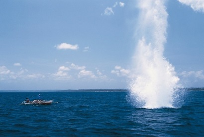 An explosion in the water with a small fishing boat nearby