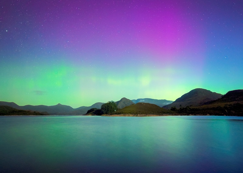 Green and pink Aurora Australis shimmering over waters in Tasmania