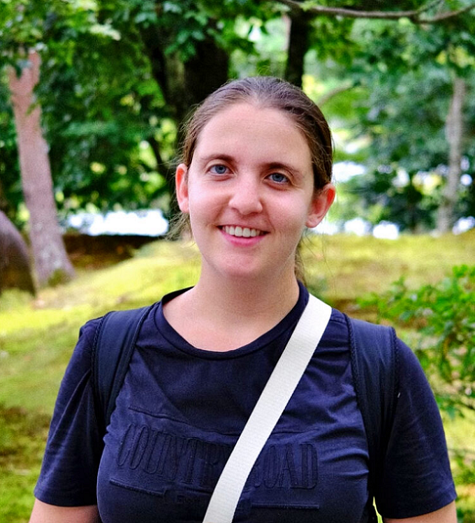 Portrait of a person in a blue shirt against the green background of a park.
