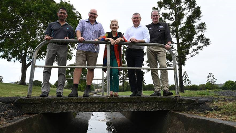 CSIRO’s Dr Jai Vaze, Lismore Mayor Steve Krieg, Lismore MP Janelle Saffin, Emergency Management Minister Murray Watt and Brendan Moon from the National Emergency Management Agency (NEMA) standing on a bridge together in Lismore in February 2023.