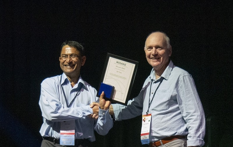 Dr Jai Vaze receives his MSSANZ award from Society member Prof Tony Jakeman in Darwin, 2023. Pictured are jai and Tony shaking hands on stage.
