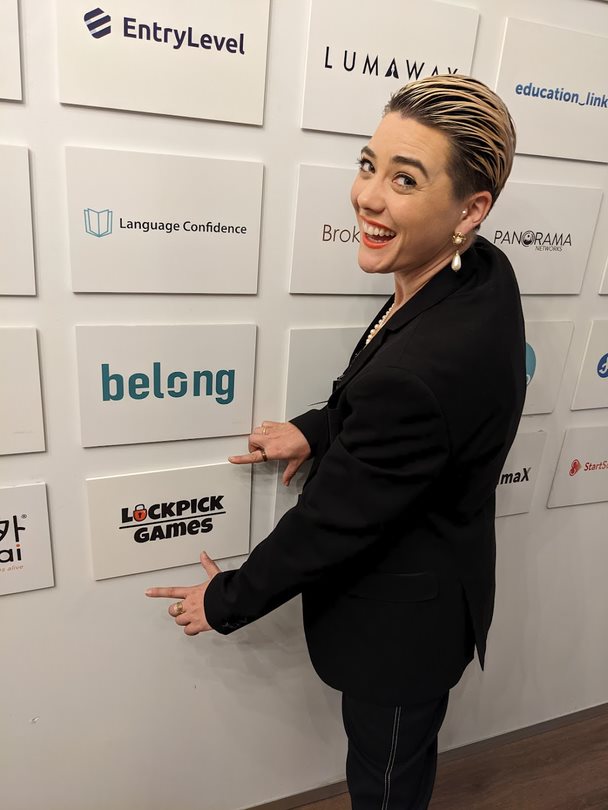 Young woman wearing a black suit looks at a name on a media wall. 