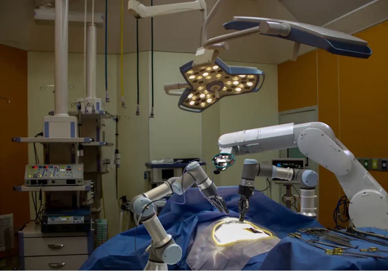 An operating room with no people and only several robot arms hovering above a patient
