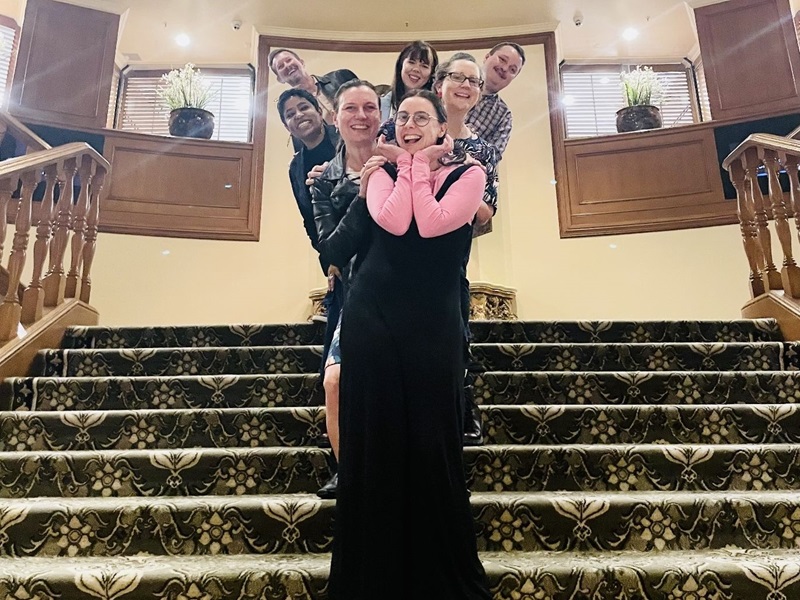 Summer and her team of six pose on a staircase. Front to back: Tess Corkish, Summer Goodwin, Felicity Kelly, Smriti Daniel, Rachel Lee, Henry Stentiford and Elendil Archer.
