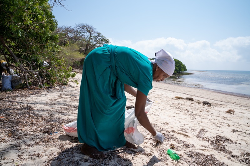 Woman cleaning up a beach in Kenya
