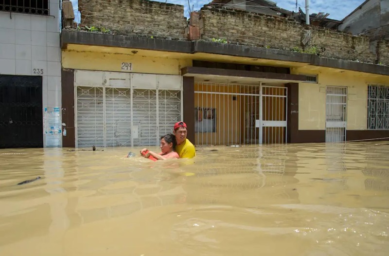 man helps woman through floodwaters
