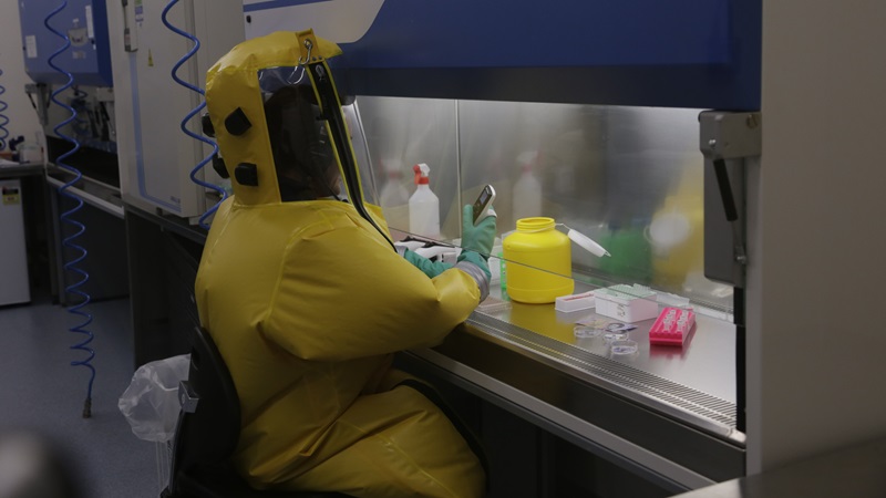 A woman in a full suit works in a laboratory. 