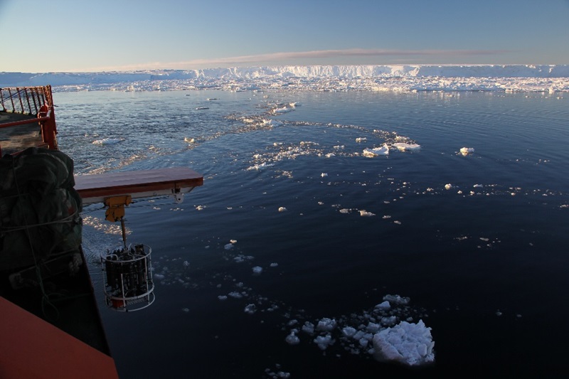 A red ship deploying an instrument surrounded by ice and water.  