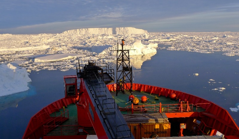 A red ship in the ocean surrounded by ice.