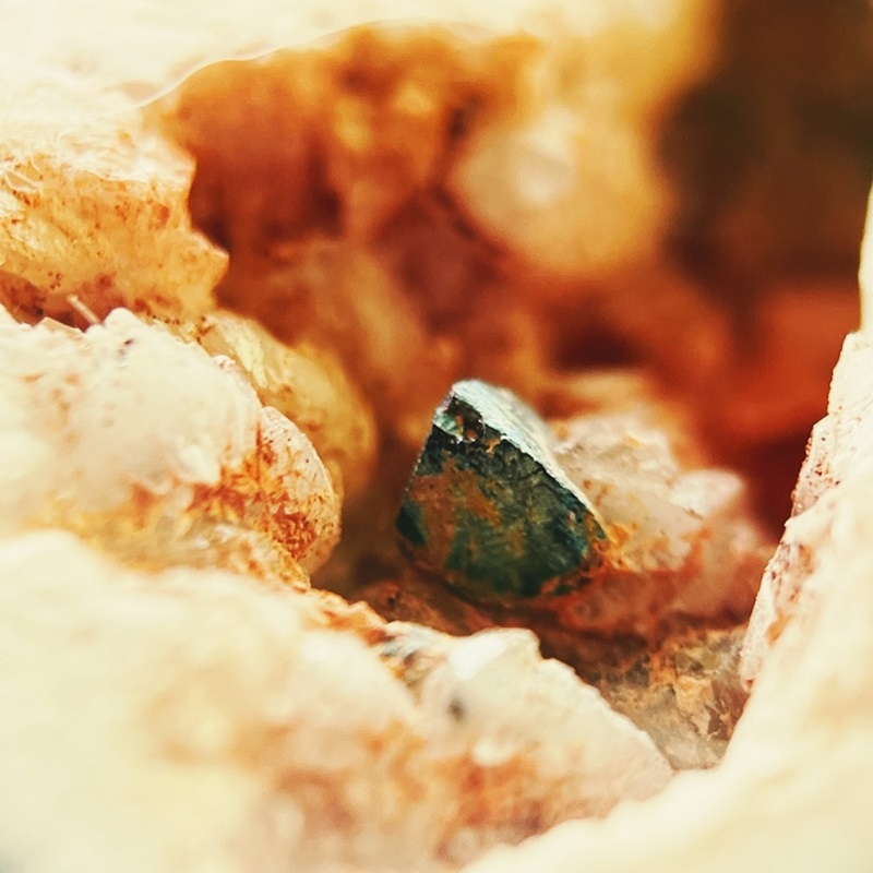 Green and yellow coloured rock surrounded by clear quartz