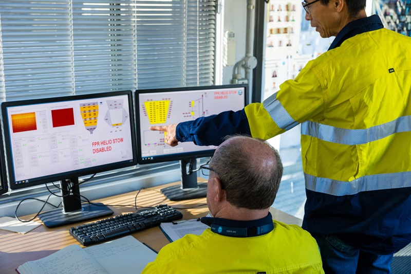 Two CSIRO staff in hi-vis PPE clothing consult two computer monitors with solar thermal information on the screens.