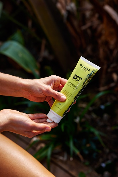 A person pouring Ochre Sun sunscreen from a tube