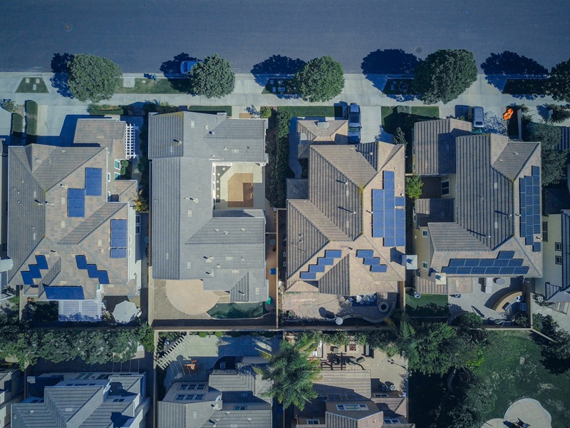 An aerial view of houses with solar panels on them. 
