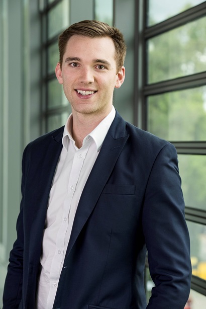 A young man in a suit smiles for the camera. 