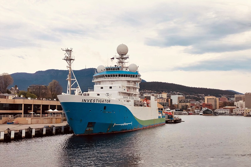 A blue and white ship at a wharf.
