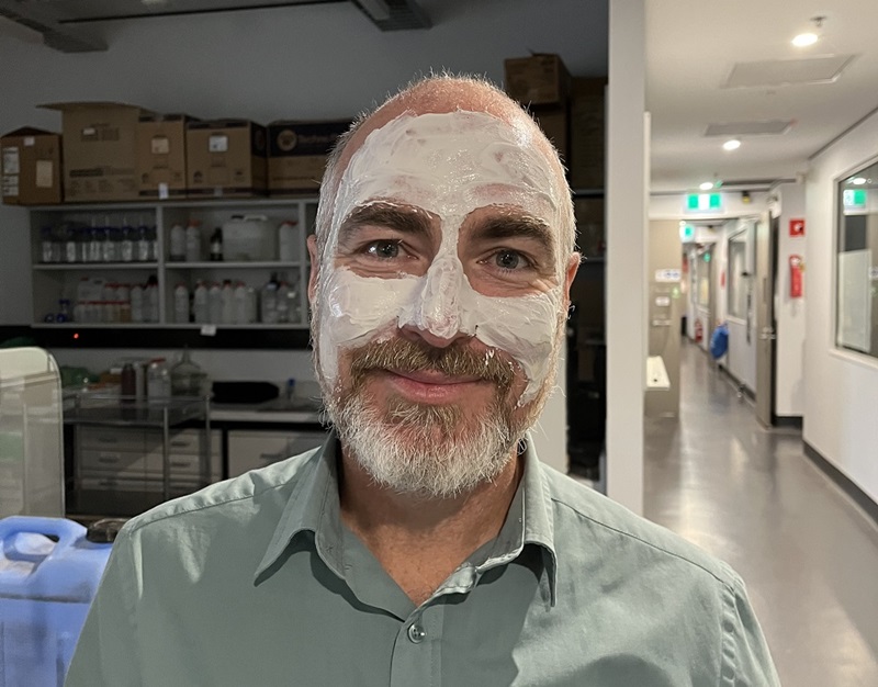 Bearded man with a clay mask applied to face