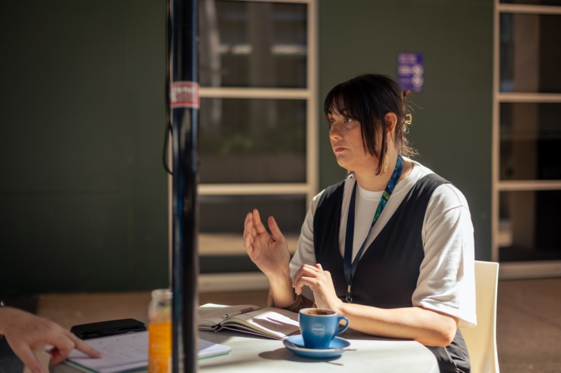 Mibu Fischer sitting at a chair with a coffee cup.